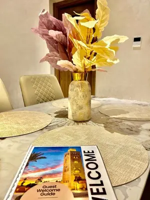 a magazine sitting on a table with a vase with flowers at Appartement Moderne - Accès Piscines et Fitness in Marrakech
