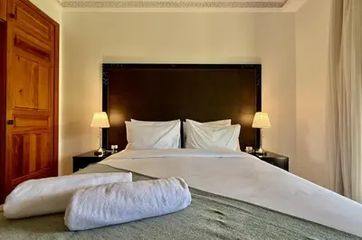 a bedroom with a large white bed with two lamps at Apartment with big private garden in Palmeraie in Marrakech