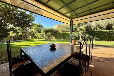 a table and chairs under a covered patio at Apartment with big private garden in Palmeraie in Marrakech