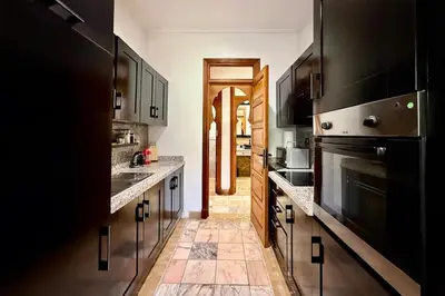 a large kitchen with black cabinets and a large oven at Apartment with big private garden in Palmeraie in Marrakech