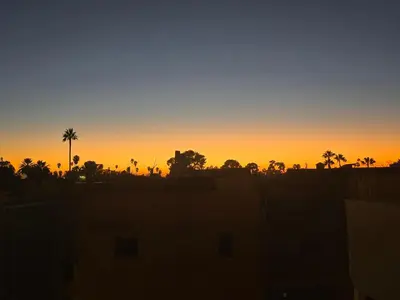 an orange sunset with palm trees in the background at Riad Alaya by Maison Amellal in Marrakech