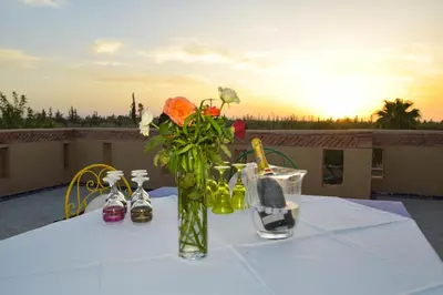 a table with a vase of flowers on a table at Bluegreen Guest House Marrakech in Aït Amara