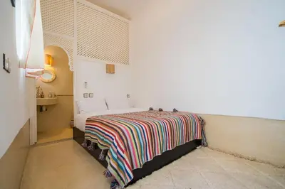 a bedroom with a bed with a colorful blanket on it at Riad privé 3 chambres, pdj inclus, 10 min Jema El Fna in Marrakech
