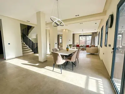 a dining room and living room with a table and chairs at Villa CAN 2025 & Chill Marrakech in Dar Caïd Layadi