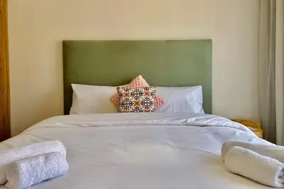 a white bed with a green headboard and two pillows at Domaine de Noria with terrace and Pools in Marrakech