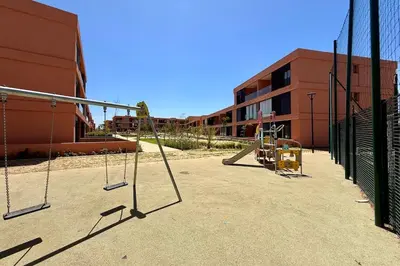 an empty playground with swings in front of a building at Domaine de Noria with terrace and Pools in Marrakech