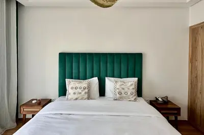 a bedroom with a large bed with a green headboard at Domaine de Noria with terrace and Pools in Marrakech