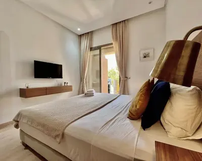 a bedroom with a bed with a lamp and a television at Prestigia Agate 5 minute from Airport in Marrakech