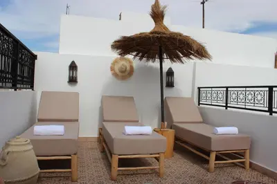 two chairs and an umbrella on a patio at Riad de charme privatisé au cœur de la médina in Marrakech