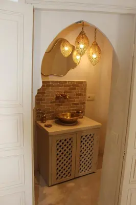 a bathroom with a sink and lights on a wall at Riad de charme privatisé au cœur de la médina in Marrakech
