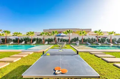 a resort with a pool with chairs and umbrellas at Prestige Twin Villa with Splendid View in Marrakech
