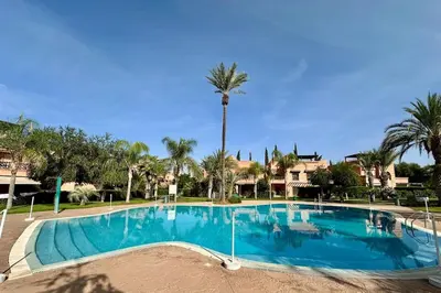 a large swimming pool with a palm tree in the background at Atlas Golf Resort with Terrace and Pools in Marrakech