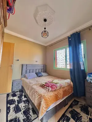 a bedroom with a large bed with blue curtains at Modern Apt 10min Airport Balcony & Wi-Fi in Marrakech