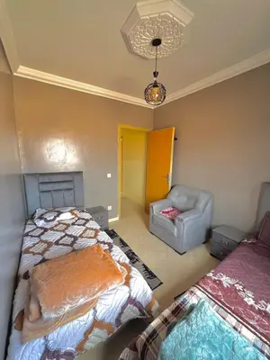a room with two beds and a chair in it at Modern Apt 10min Airport Balcony & Wi-Fi in Marrakech