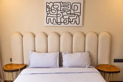 a bed with a large padded headboard and two tables at Villa terracotta in Marrakech
