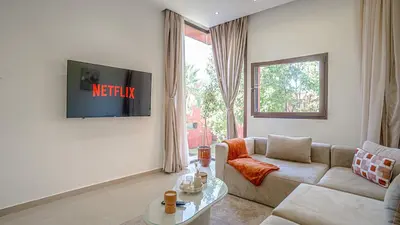 a living room with a couch and a tv on a wall at Appart calme & central, piscine, proche médina et place Jemaa El Fna in Marrakech