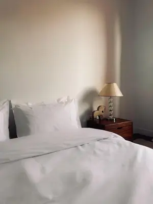 a bed with white sheets and a lamp on a table at Designer apartment with south-facing terrace in Marrakech