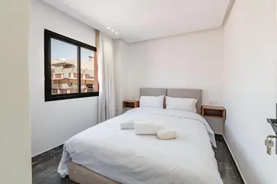 a bedroom with a large white bed with a window at Appartement au cœur de Guéliz in Marrakech