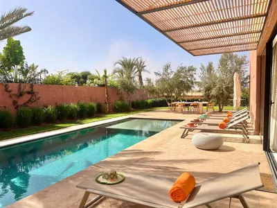 a swimming pool with chairs and a table next to a house at Villa AYA - Moderne & Chic in Sraghna