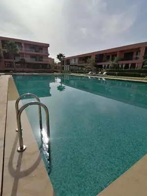 a swimming pool in front of a building at Beautiful Apartment with Pool View Noria Golf in Marrakech