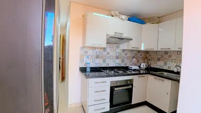 a small kitchen with white cabinets and a stove at דירה