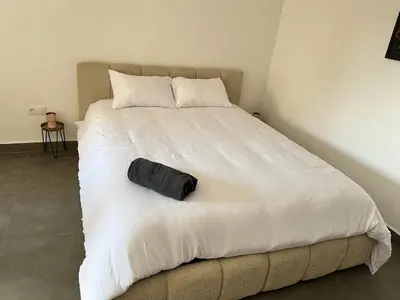 a large white bed with a black pillow on it at Evasion à Marrakech very centrally located in Marrakech