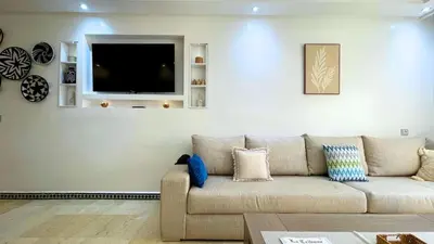a living room with a couch and a flat screen tv at Beautiful Bright Apartment Victor Hugo District in Marrakech