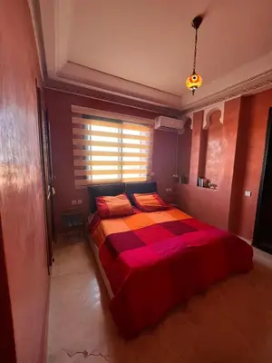 a bedroom with a bed with a red and black comforter at App RIAD JAWHARA in Marrakech
