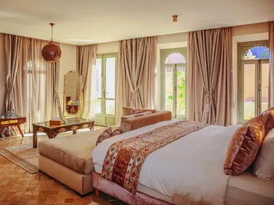 a bedroom with a bed and a chair and windows at Kasbah La Moun Luxury Riad & Spa in Marrakech