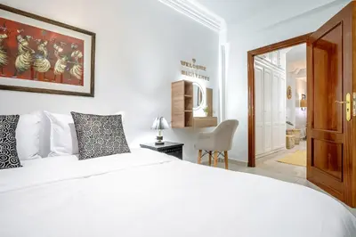 a bedroom with a white bed and a chair at Appartement de charme à Gueliz - Centre Marrakech in Marrakech