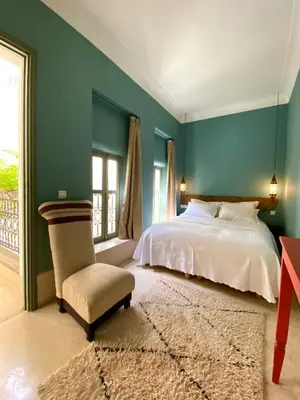 a bedroom with a bed and a chair and a window at Riad Dar Bou Seta - Small Riad in Marrakech