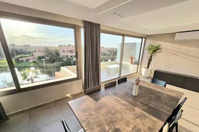 a large room with a table and large windows at Penthouse Marrakech Village avec vue Panoramique sur le Lac in Marrakech