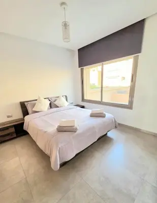a bedroom with a large bed with two towels on it at Penthouse Marrakech Village avec vue Panoramique sur le Lac in Marrakech