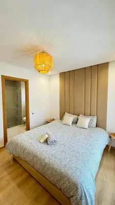 a bedroom with a large bed and a chandelier at Magnifique appartement in Marrakech