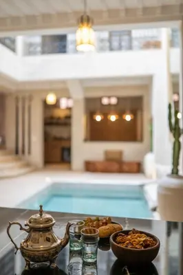 a tea kettle and bowls of food on a table next to a pool at Riad Kasbah Lover Swimming pool breakfast included in Marrakech