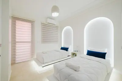 two beds in a bedroom with white walls and blue pillows at Cozy Mykonos 2BR Apartment in Marrakech