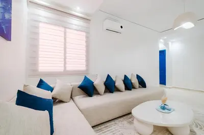 a living room with a couch with blue pillows at Cozy Mykonos 2BR Apartment in Marrakech