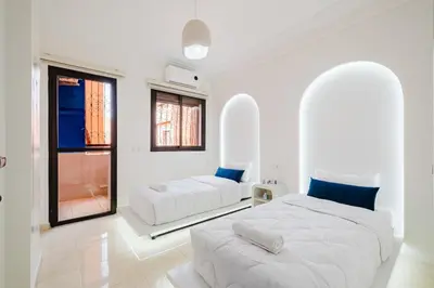 a white bedroom with two beds and a window at Cozy Mykonos 2BR Apartment in Marrakech