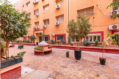 a courtyard of a building with trees and benches at Cocon Urbain centre-ville et confort in Marrakech