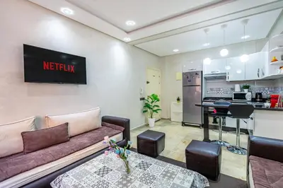 a living room with a couch and a kitchen at Cocon Urbain centre-ville et confort in Marrakech