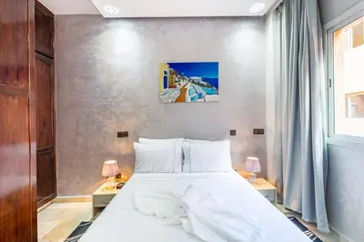 a bedroom with a large white bed with two lamps at Cocon Urbain centre-ville et confort in Marrakech