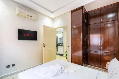 a bedroom with a bed and a wooden cabinet at Cocon Urbain centre-ville et confort in Marrakech