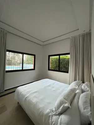 a bedroom with a large white bed with two windows at Palmeraie Cozy Apartment in Marrakech
