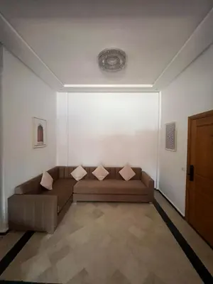 a living room with a brown couch in a white wall at Palmeraie Cozy Apartment in Marrakech