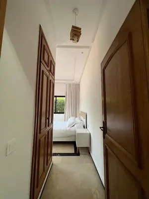 a hallway with a bedroom with a bed and a door at Palmeraie Cozy Apartment in Marrakech