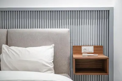 a bed with a white pillow and a nightstand with a alarm clock at Appartement 3 Chambres Luxe au Cœur de Guéliz in Marrakech