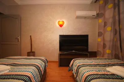 a bedroom with two beds and a heart light on the wall at Superbe Appartement 3 pieces à Majorelle in Marrakech