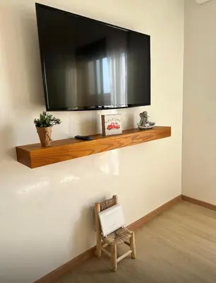 a tv on a wall with a chair under a shelf at Serenity Loft in Marrakech