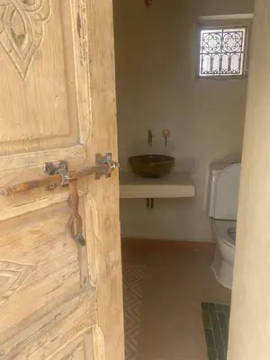 a bathroom with a sink and a wooden door at Dar Aji, votre maison d'architecte privatisée en médina in Marrakech