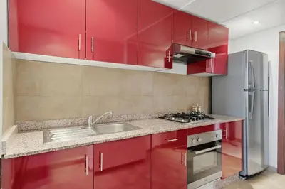 a kitchen with red cabinets and a sink at Modern apartment, swimming pool and sports in Marrakech